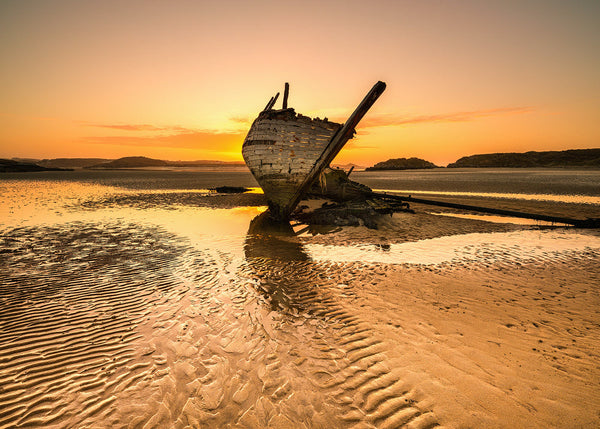 Cara Na Mara shipwreck at sunset on sandy beach Donegal Ireland with golden light and tidal patterns landscape photography