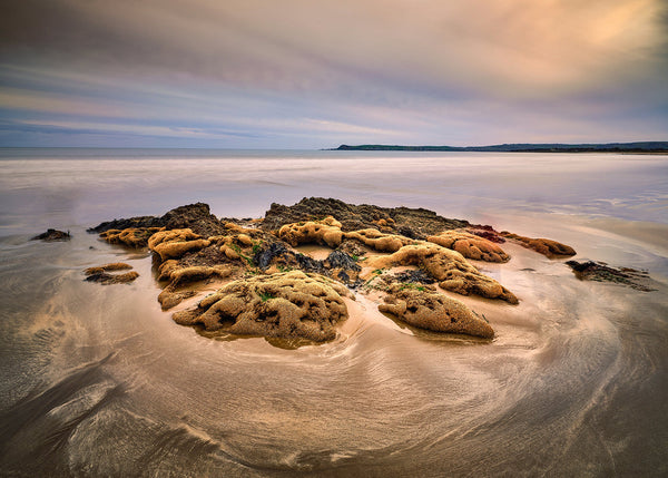 Clonea Bay beach in County Waterford with seaweed foreground and soft long exposure Atlantic water