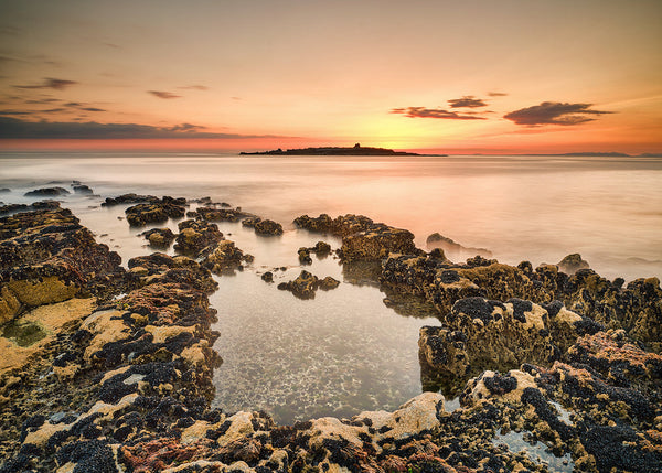 Golden sunset over Atlantic Ocean at Doolin County Clare Ireland with moss covered rocks and long exposure water