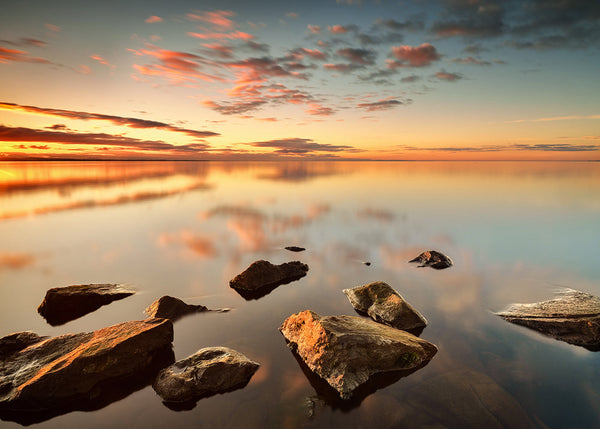 Cranfield on Lough Neagh sunrise with rocks in calm water and soft pastel sky Northern Ireland