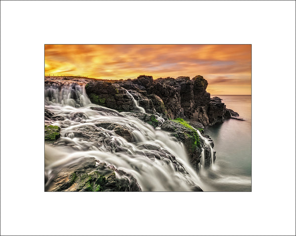 Spring sunset at Dunseverick Waterfall on the Causeway Coast, majestic waterfall flowing into the Atlantic Ocean and at certain times of the year the sunsets are spectacular by Irish landscape photographer John Taggart.