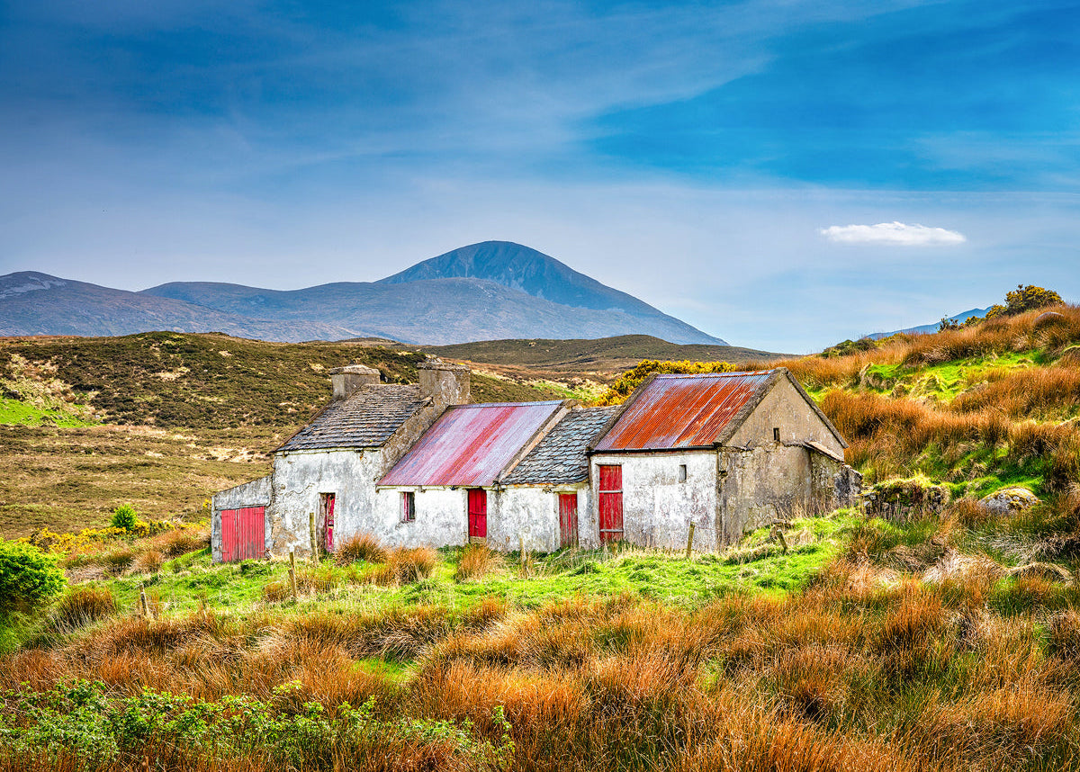 Nestled amidst the rolling hills and golden grasses of County Donegal, Ireland, this weathered cottage stands as a quiet witness to generations past. By John Taggart Landscapes