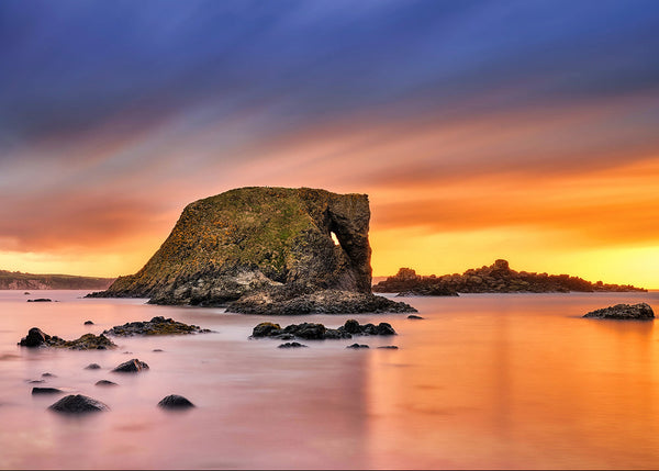 Elephant Rock sea arch in Donegal at sunset with glowing orange sky and calm long exposure water, Irish landscape photography