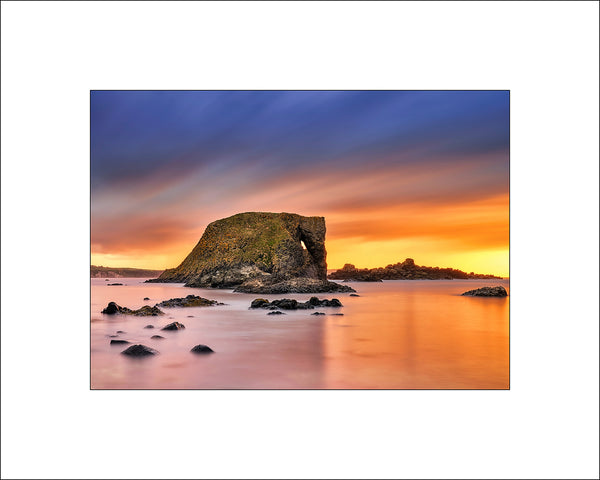 Elephant Rock near Ballintoy on Antrim's Causeway Coast on a beautiful calm evening when the suns rays reflect off the Atlantic Ocean by John Taggart Irish Landscape Photographer