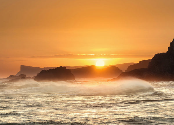 Golden sunset over crashing waves at Fair Head on the County Antrim coast in Northern Ireland.