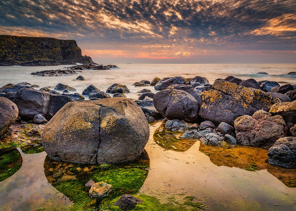 Giant’s Causeway boulders at sunset with golden sky and tidal pools, County Antrim Northern Ireland coastal landscape