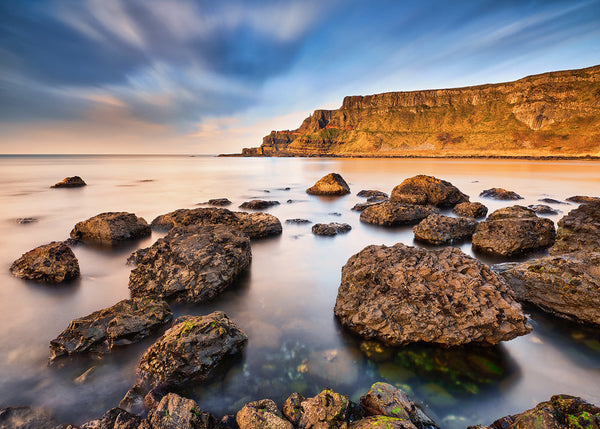 Giant’s Causeway coastal rocks at golden hour Northern Ireland long exposure seascape with cliffs and calm water
