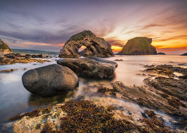 Ballintoy sea arch and coastal rocks at sunset on the Causeway Coast in Northern Ireland by John Taggart Landscapes