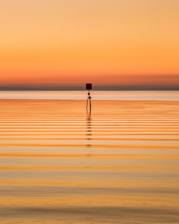 Minimalist sunset photo of a lone lake navigation beacon surrounded by soft water ripples at Lough Neagh, County Antrim.