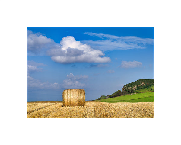 Blue skies and a lone hay bale in the fields near Ballintoy Harbour in County Antrim, Northern Ireland by John Taggart Landscapes