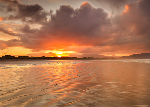 Sunset over a beach with reflective water and colorful clouds at Inch Strand County Kerry Ireland