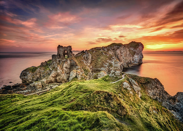 Kinbane Castle ruins at sunrise on Antrim Coast cliffs with golden sky and calm sea Northern Ireland landscape