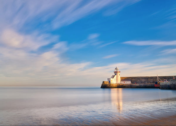 Balbriggan lighthouse reflection at sunset with smooth sea long exposure Ireland