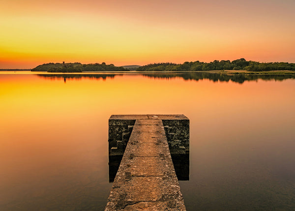 Lough Key pier at sunset in County Roscommon Ireland with calm lake reflections and golden sky long exposure landscape photography