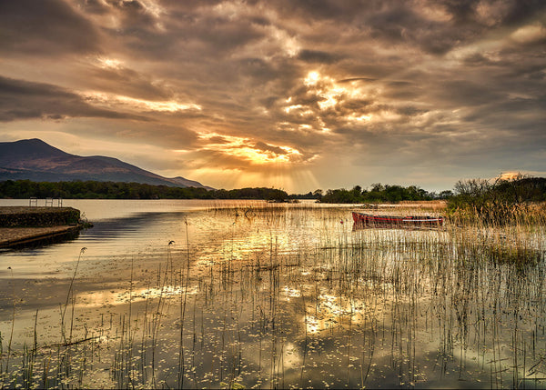 Lough Leane sunset with dramatic sun rays and boat reflections in Killarney National Park County Kerry Ireland landscape photography
