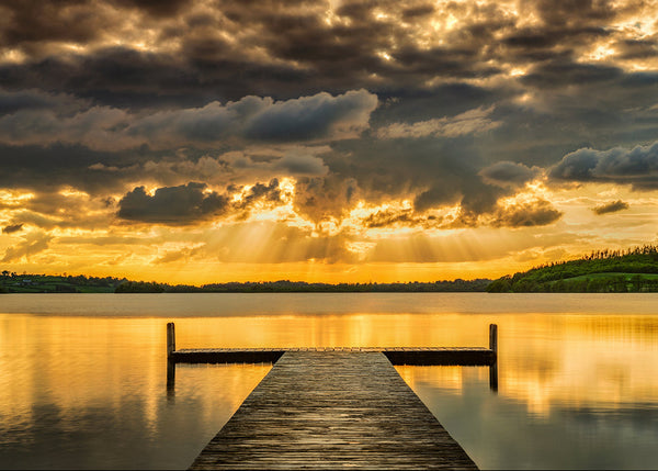 Golden sunset over Lough Lene in County Westmeath Ireland with wooden pier and dramatic sun rays