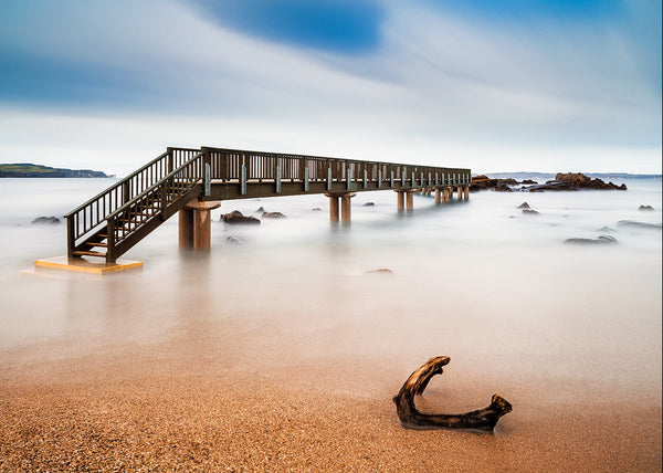 Pans Rock pier Ireland wooden boardwalk over calm sea long exposure minimal coastal landscape with soft tones