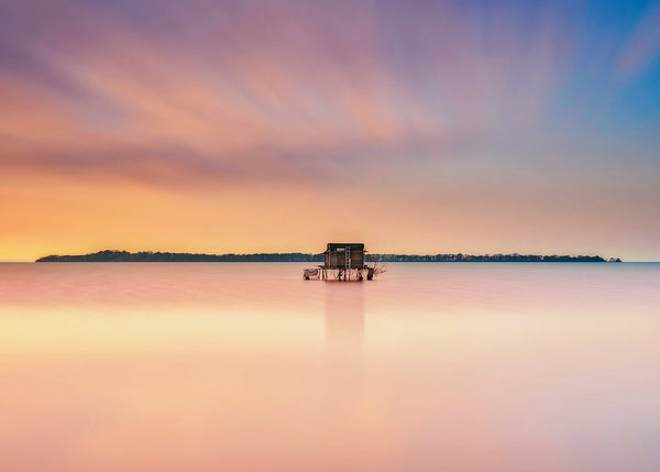 Rams Island Lough Neagh sunset with calm pastel sky and small hut reflected in water Irish landscape photography