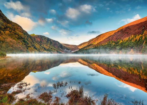 Glendalough lake reflection Wicklow Ireland autumn landscape with mountains, forest colours and mist over still water mirrored reflection