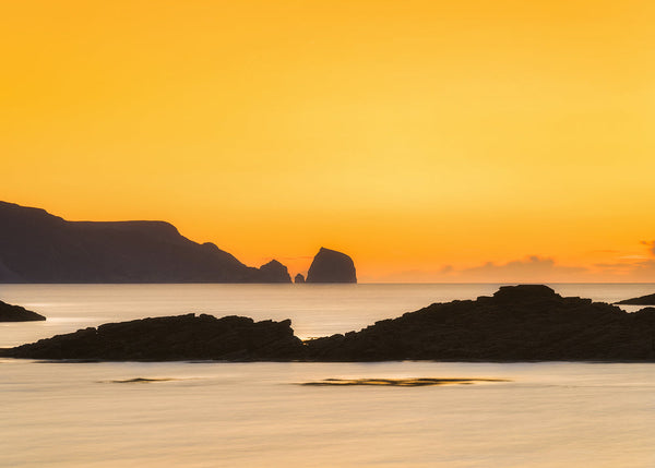 Golden sunset over Rosbeg Beach County Donegal with sea stacks silhouetted against orange sky