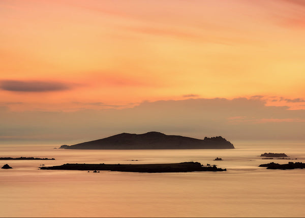 The Sleeping Giant island silhouette at sunset off the coast of County Kerry Ireland with calm sea and warm golden sky