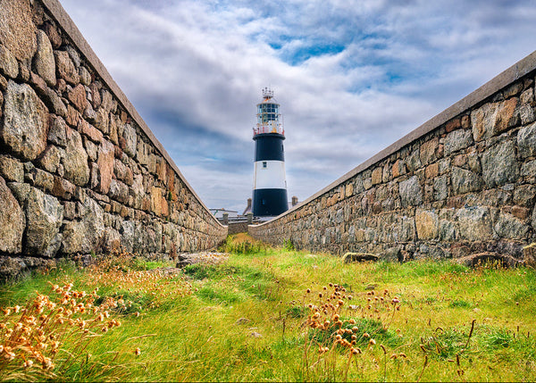 Lighthouse between two stone walls with a cloudy sky on Tory Island County Donegal