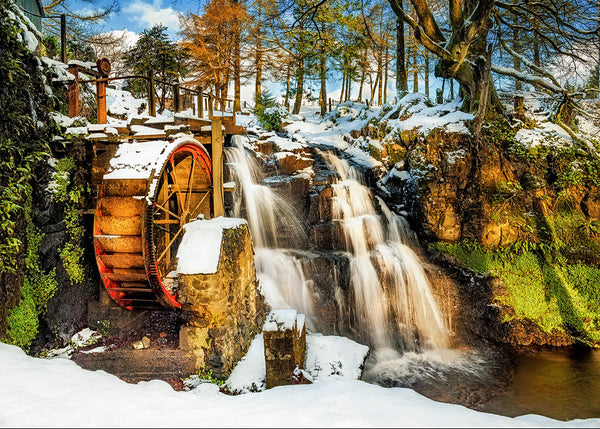 Old water wheel beside snowy waterfall in woodland Northern Ireland winter landscape with flowing stream and trees