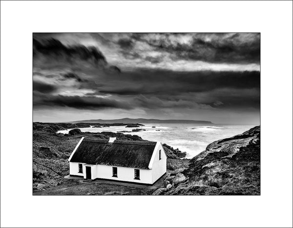 A quint little white washed thatched cottage on a stormy evening on the Wild Atlantic Way in Donegal by John Taggart Landscapes 